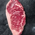 Rohes Striploin-Steak, Rindfleisch-Metzgerei-Schnitt. Schwarzer Hintergrund. Ansicht von oben. von food fotograf hannover.