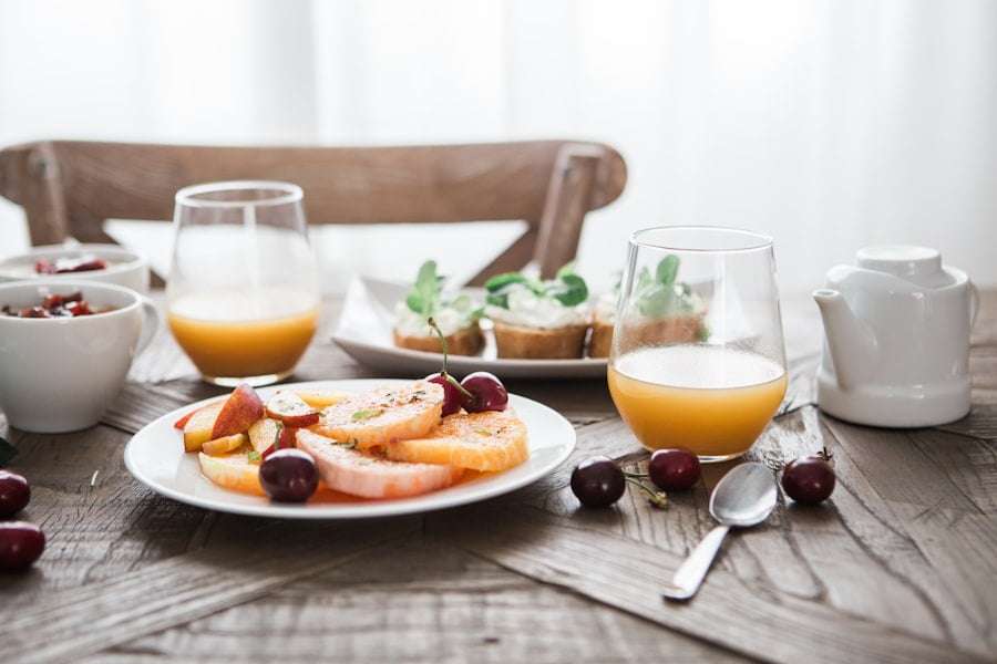 Der Food Fotograf - Ein Frühstückstisch mit Tellern voller Grapefruitscheiben mit Kirschen, Toast mit grüner Garnitur, Schalen mit Joghurt und.