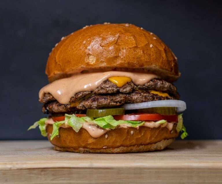 Der Food Fotograf - Eine Nahaufnahme eines Doppel-Cheeseburgers auf einer Holzoberfläche.