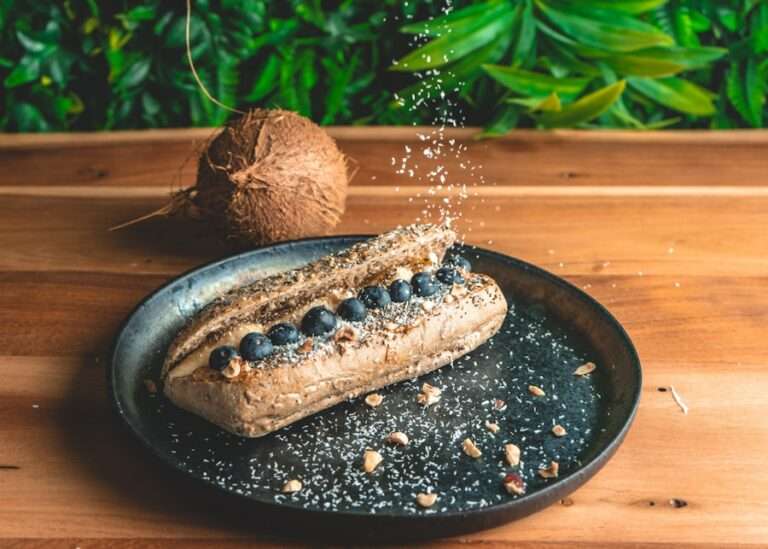 Der Food Fotograf - Ein Sandwich auf einem Teller, gefüllt mit Blaubeeren und bestreut mit Kokosraspeln.
