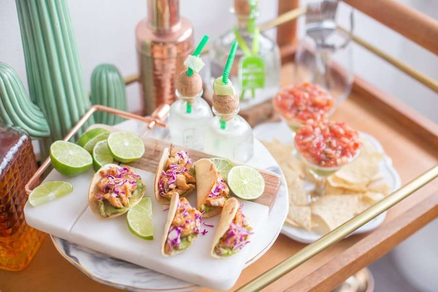 Der Food Fotograf - Auf einem kleinen Servierwagen aus Holz steht ein Tablett mit Mini-Tacos, garniert mit Limettenspalten und geraspeltem Gemüse.