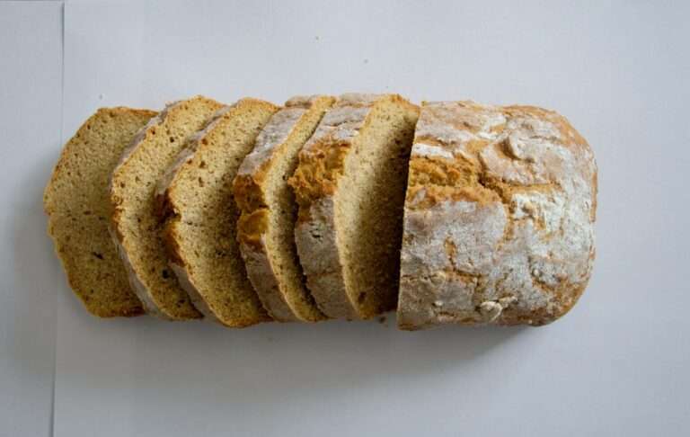 Der Food Fotograf - Ein teilweise angeschnittener Laib Brot auf einer weißen Oberfläche.