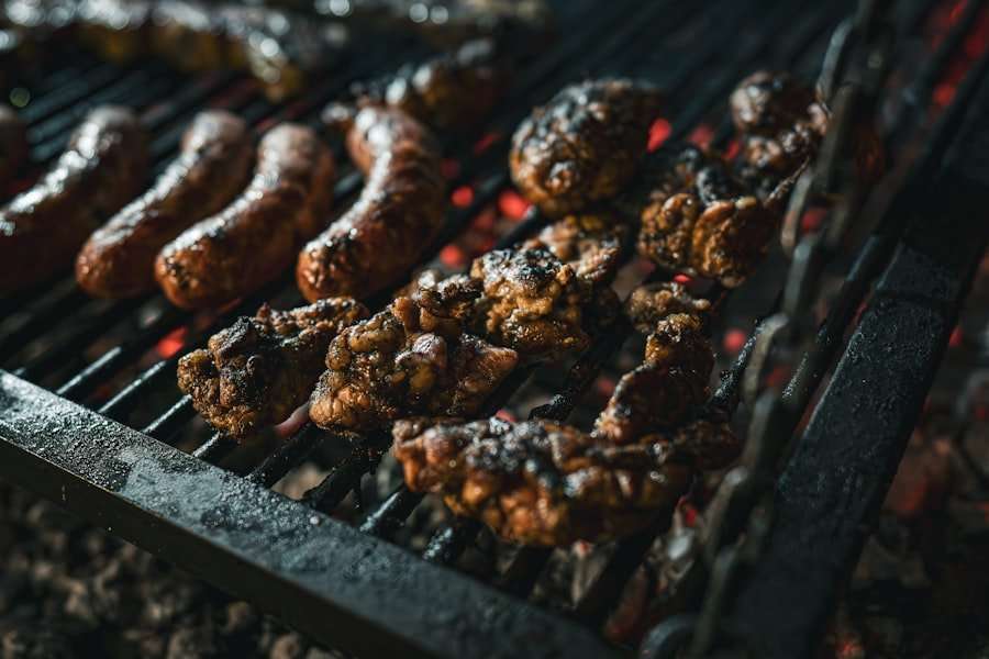 Eine Nahaufnahme eines Grills mit verschiedenen Fleischsorten, darunter Würstchen und marinierte Fleischstücke, die über glühenden Kohlen gegart.