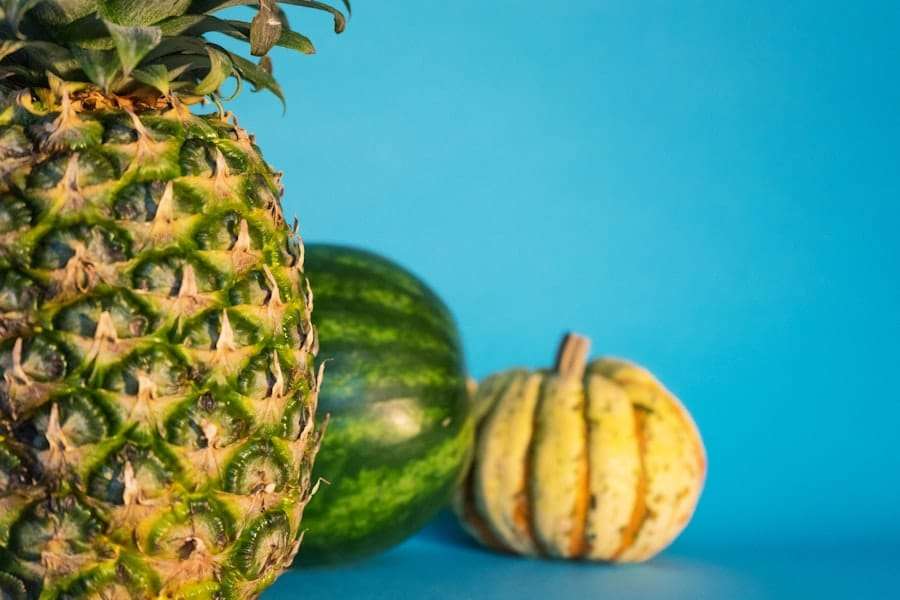 Eine Nahaufnahme einer Ananas mit einem Teil einer Wassermelone und einem kleinen Kürbis im Hintergrund.