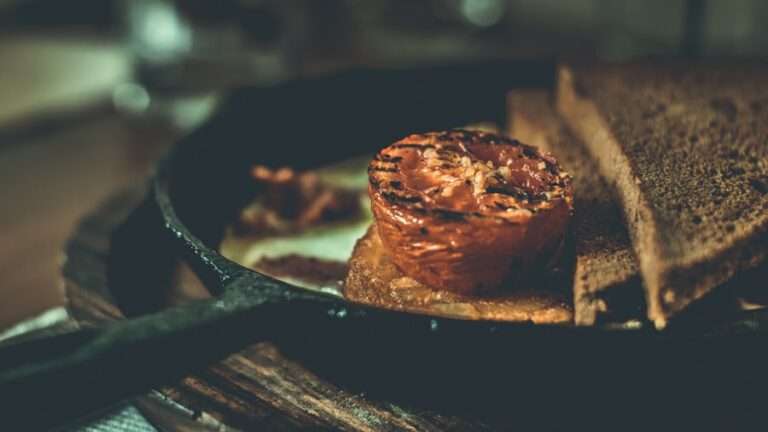 Der Food Fotograf - Eine gegrillte halbe Tomate liegt zusammen mit zwei weiteren Brotscheiben auf einer Brotscheibe in einer Pfanne.
