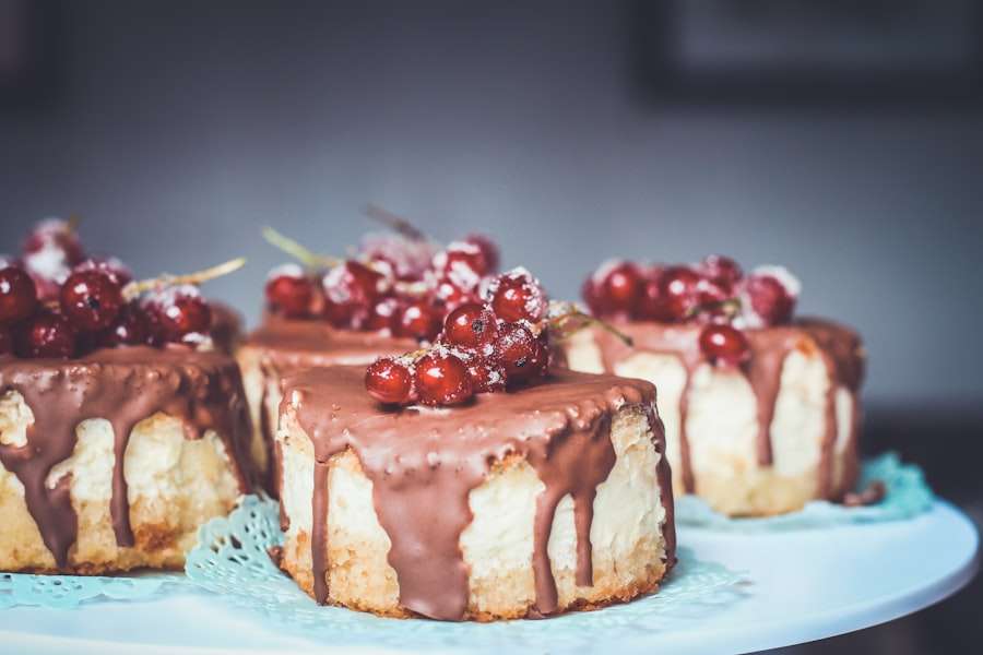 Der Food Fotograf - Vier kleine Käsekuchenscheiben, jede mit Schokoladenglasur und einer Traube roter Johannisbeeren überzogen, werden auf einer.