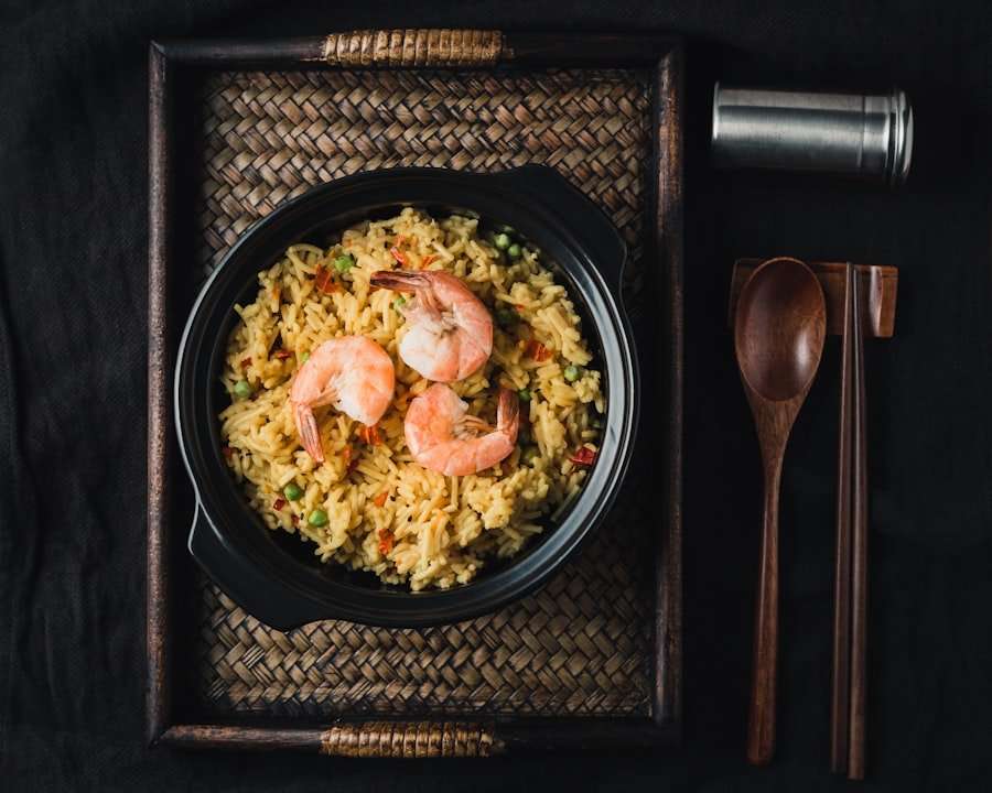 Der Food Fotograf - Eine schwarze Schüssel mit gebratenem Garnelenreis steht auf einem geflochtenen Tablett.