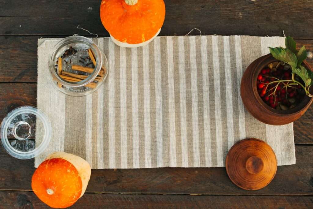 Eine rustikale Tischdekoration, die sich ideal als Hintergrund für Food-Fotografie eignet, besteht aus einem beige-weiß gestreiften Tischläufer.