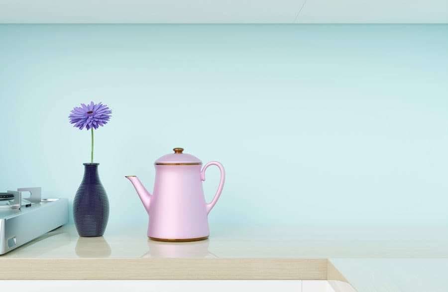 Eine pastellfarbene Küchenszene mit einer violetten Vase mit einer einzelnen violetten Blume und einer rosa Teekanne mit goldenem Deckel und.