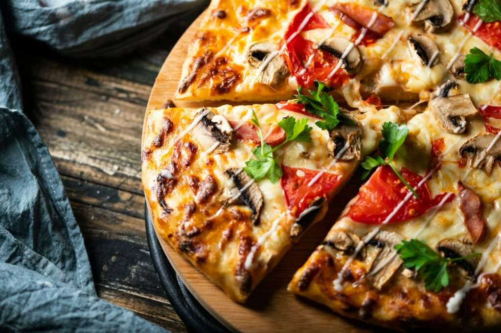 Eine Nahaufnahme einer geschnittenen Pizza auf einem hölzernen Servierbrett.