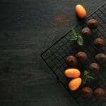 Auf einem Abkühlgitter sind Pralinen und Kumquats ordentlich angeordnet.