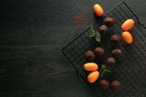 Auf einem Abkühlgitter sind Pralinen und Kumquats ordentlich angeordnet.